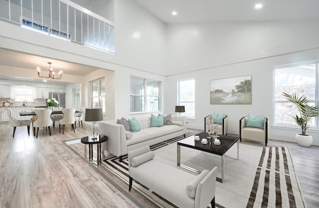 living area with high vaulted ceiling, light wood finished floors, recessed lighting, and an inviting chandelier