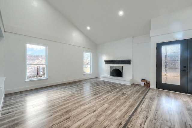 unfurnished living room featuring high vaulted ceiling, recessed lighting, a fireplace, wood finished floors, and baseboards