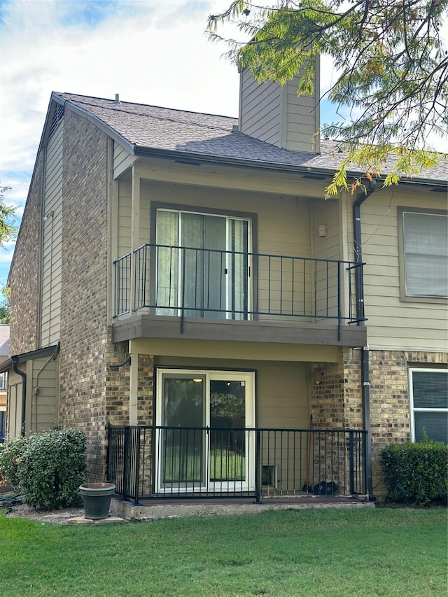 back of house with a balcony and a lawn