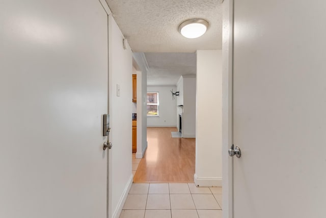 corridor with a textured ceiling and light tile patterned floors