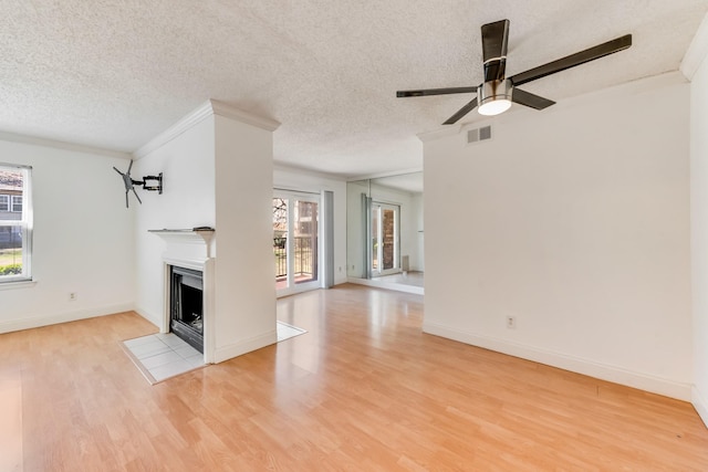 unfurnished living room featuring crown molding, light hardwood / wood-style floors, a healthy amount of sunlight, and a textured ceiling