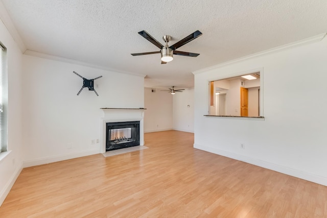 unfurnished living room featuring ceiling fan, ornamental molding, light hardwood / wood-style floors, and a textured ceiling