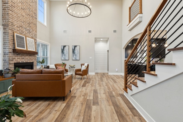 living area with light wood-type flooring, a brick fireplace, visible vents, and baseboards