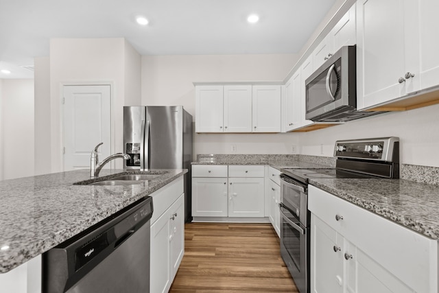 kitchen featuring stainless steel appliances, light stone countertops, white cabinets, and sink