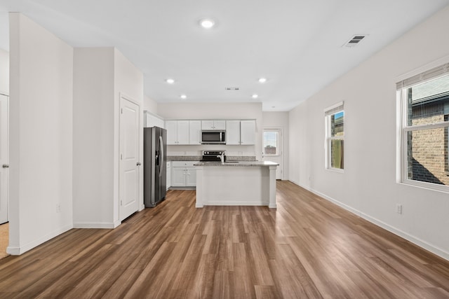 kitchen featuring white cabinets, a center island with sink, light hardwood / wood-style flooring, and stainless steel appliances