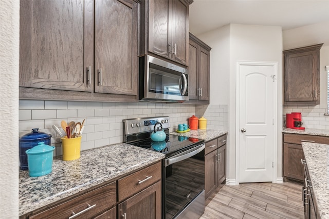 kitchen featuring tasteful backsplash, stainless steel appliances, light stone counters, and dark brown cabinetry