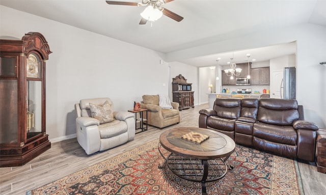 living room with ceiling fan with notable chandelier and light hardwood / wood-style flooring