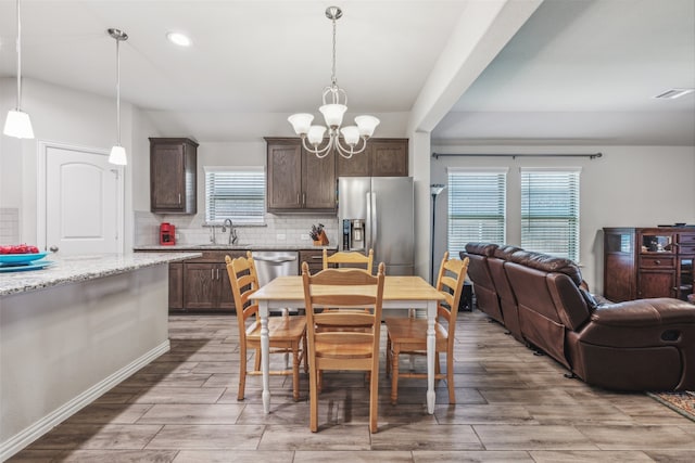 dining space with sink, a wealth of natural light, and an inviting chandelier