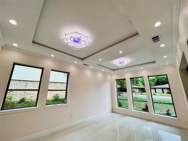 empty room with a raised ceiling and a chandelier