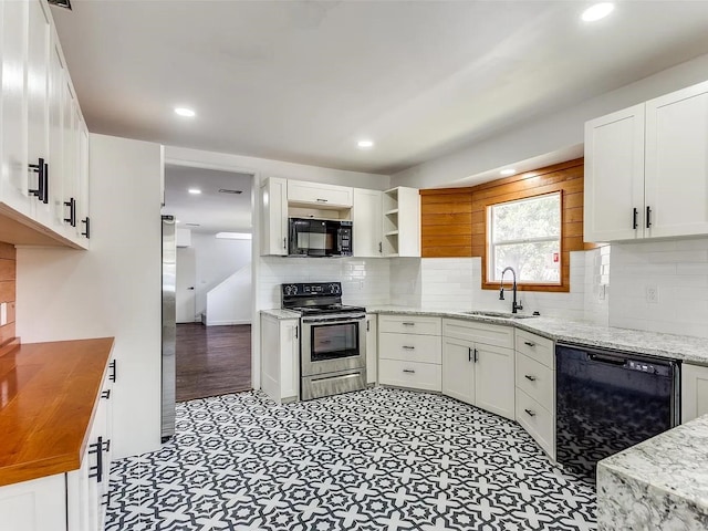 kitchen with black appliances, light stone countertops, white cabinets, backsplash, and sink