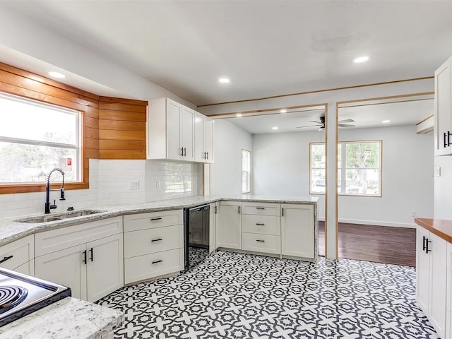 kitchen featuring kitchen peninsula, light stone countertops, ceiling fan, white cabinets, and sink