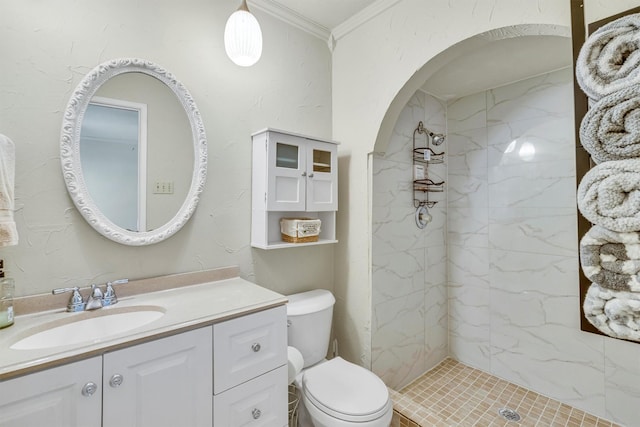 bathroom with toilet, crown molding, tiled shower, and vanity