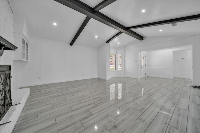 unfurnished living room with a brick fireplace and vaulted ceiling with beams