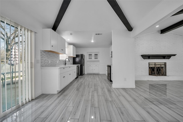 kitchen with white cabinetry, a fireplace, light hardwood / wood-style floors, decorative backsplash, and black appliances