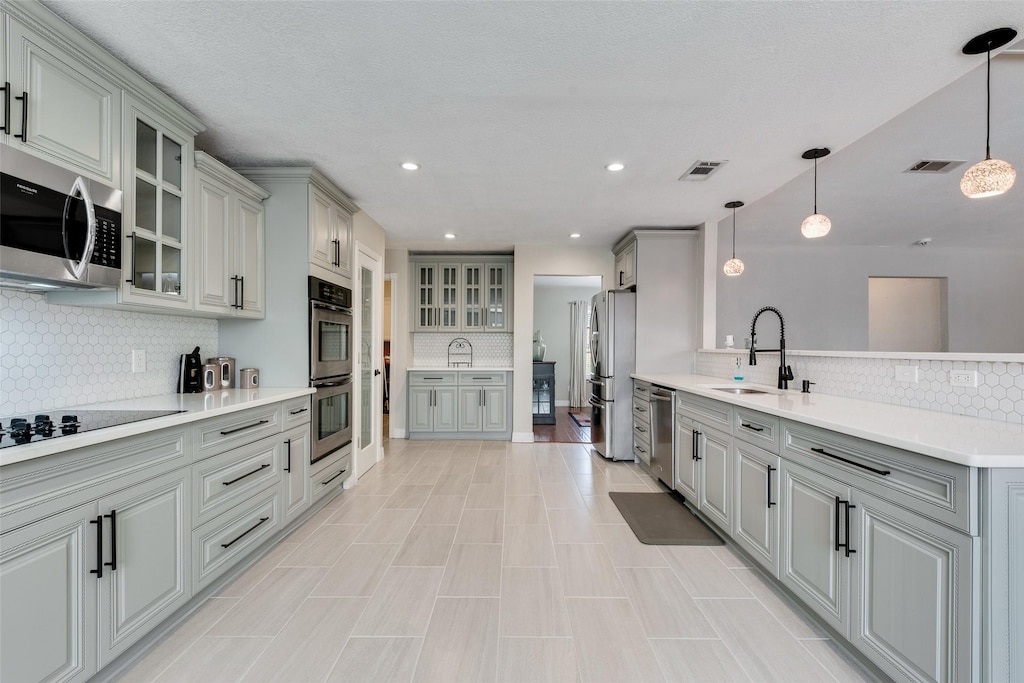 kitchen with sink, appliances with stainless steel finishes, gray cabinets, and hanging light fixtures