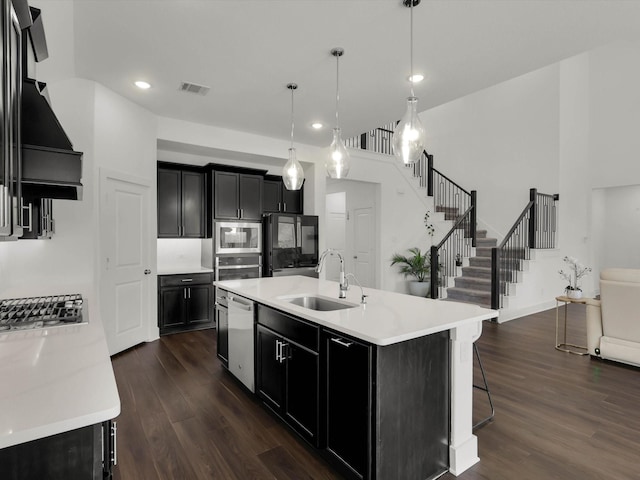 kitchen with dark wood-style floors, light countertops, appliances with stainless steel finishes, a sink, and dark cabinetry