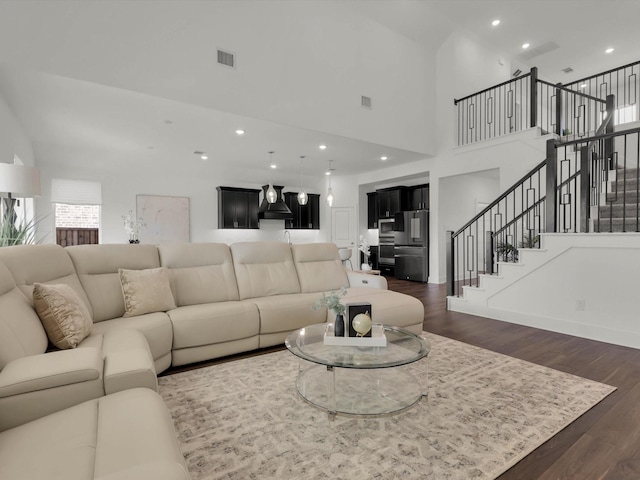 living room featuring a towering ceiling and dark wood-type flooring