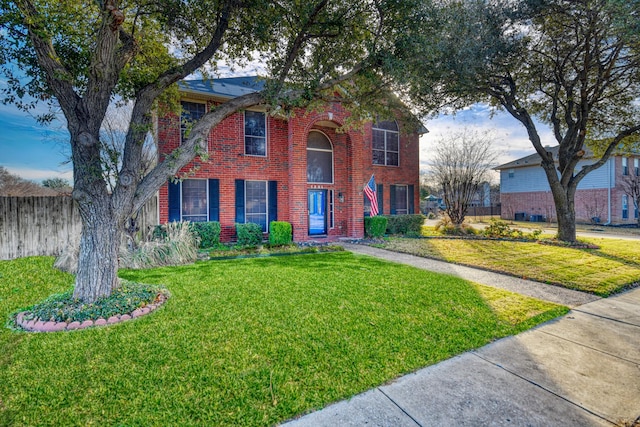 view of front of house featuring brick siding, a front lawn, and fence