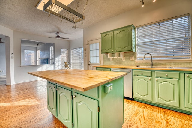 kitchen featuring butcher block countertops, light wood-style flooring, green cabinets, and stainless steel dishwasher