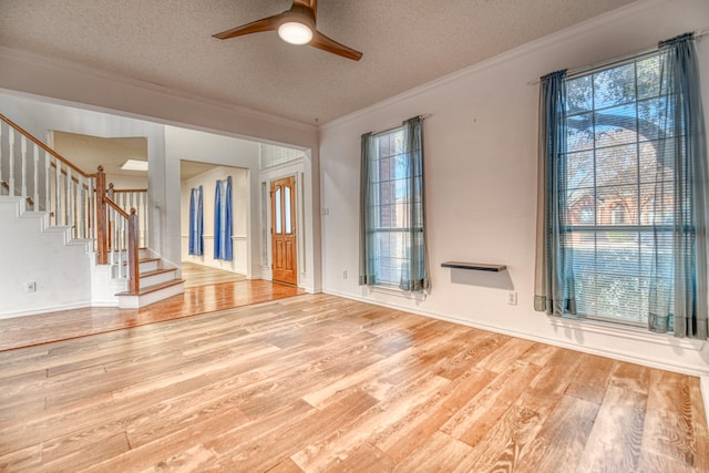 spare room with stairway, a textured ceiling, wood finished floors, and ornamental molding