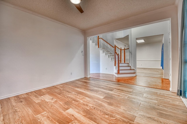 unfurnished room with stairway, a textured ceiling, crown molding, and wood finished floors