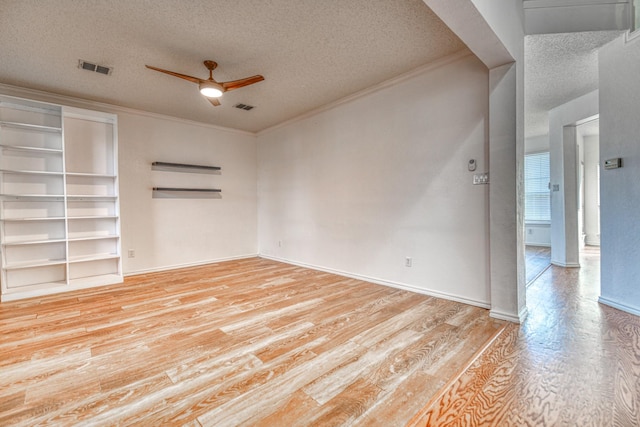 spare room featuring light wood finished floors, visible vents, a ceiling fan, and ornamental molding