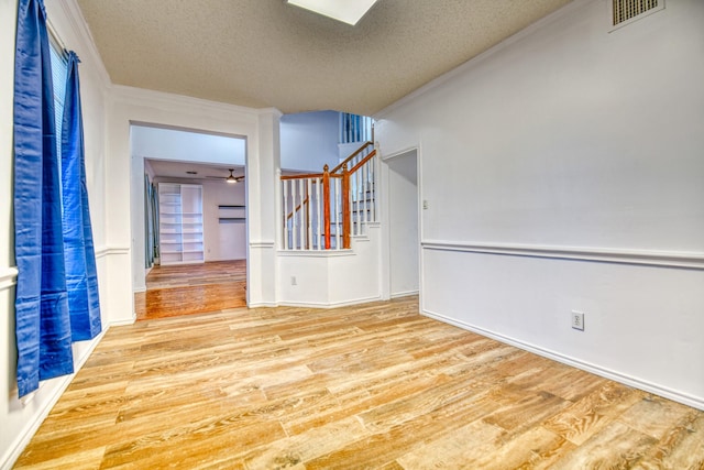 spare room featuring visible vents, a textured ceiling, wood finished floors, and stairs