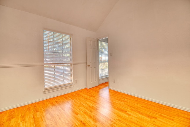 spare room featuring baseboards, high vaulted ceiling, and wood finished floors