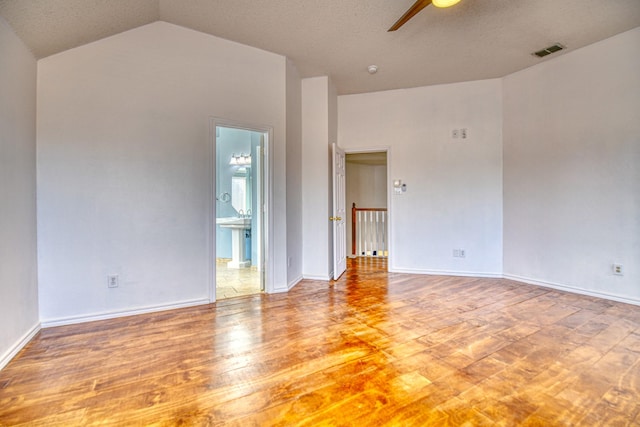 empty room featuring visible vents, wood finished floors, baseboards, ceiling fan, and vaulted ceiling