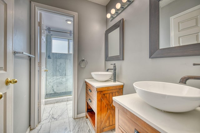 bathroom featuring a stall shower, two vanities, marble finish floor, and a sink