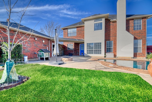 rear view of house with a patio, a yard, a fire pit, and brick siding