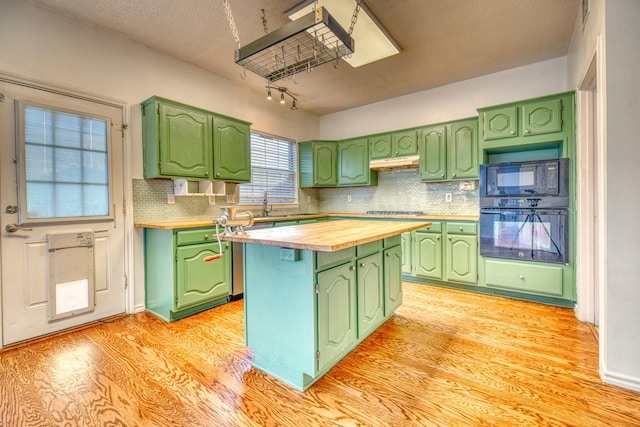 kitchen with under cabinet range hood, wooden counters, black appliances, and green cabinetry