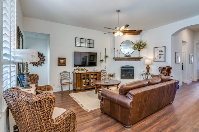 living room featuring dark wood-type flooring, ceiling fan, and a fireplace