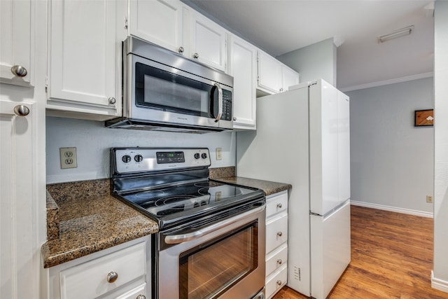 kitchen featuring stainless steel appliances, white cabinets, dark stone countertops, ornamental molding, and light hardwood / wood-style floors