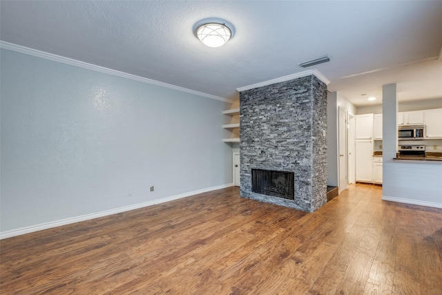 unfurnished living room with a fireplace, a textured ceiling, crown molding, and hardwood / wood-style floors