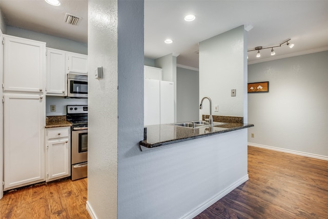 kitchen with stainless steel appliances, crown molding, white cabinetry, dark stone counters, and sink