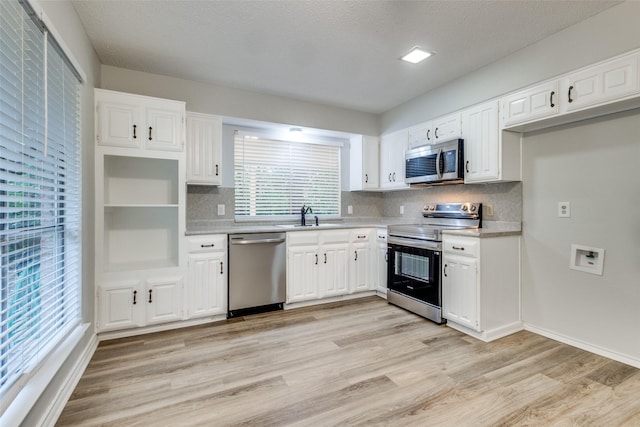 kitchen featuring sink, stainless steel appliances, white cabinetry, and light hardwood / wood-style floors