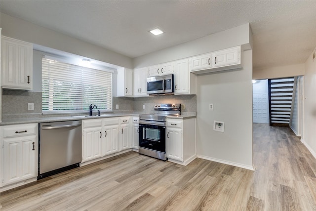 kitchen with backsplash, stainless steel appliances, white cabinets, and sink