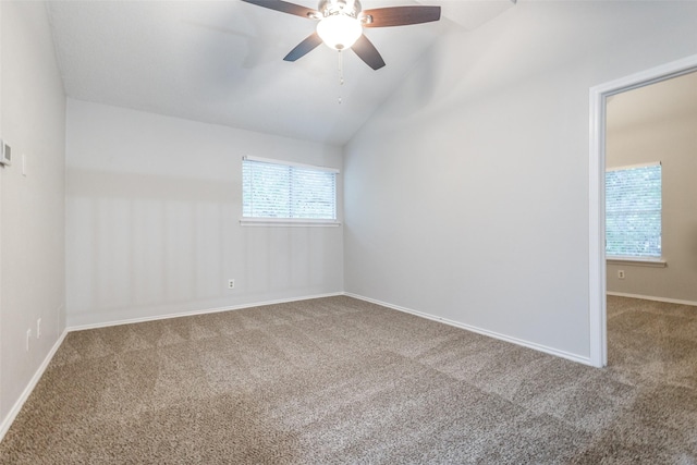 empty room featuring ceiling fan, carpet floors, vaulted ceiling, and a wealth of natural light