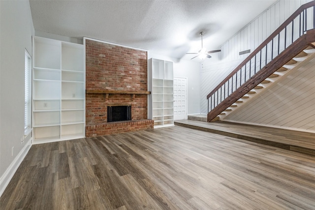 unfurnished living room featuring a fireplace, a textured ceiling, ceiling fan, and wood-type flooring