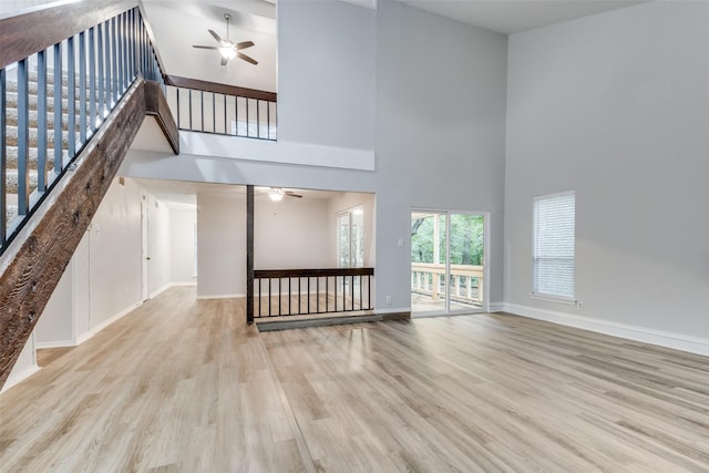 unfurnished living room featuring a high ceiling, ceiling fan, and light hardwood / wood-style flooring