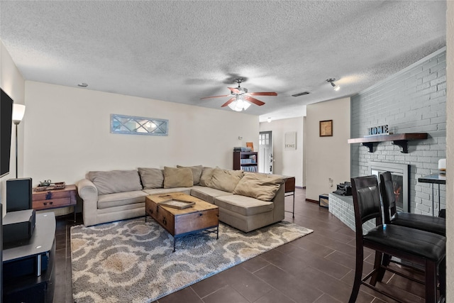 living room featuring ceiling fan, a fireplace, and a textured ceiling