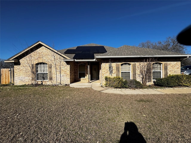 view of front of home with solar panels and a front yard