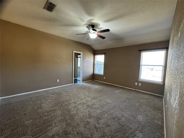 spare room with ceiling fan, lofted ceiling, carpet floors, and a textured ceiling