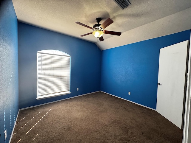 carpeted empty room with vaulted ceiling, ceiling fan, and a textured ceiling