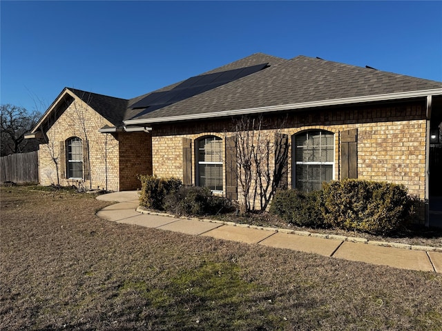 ranch-style home with a front lawn and solar panels