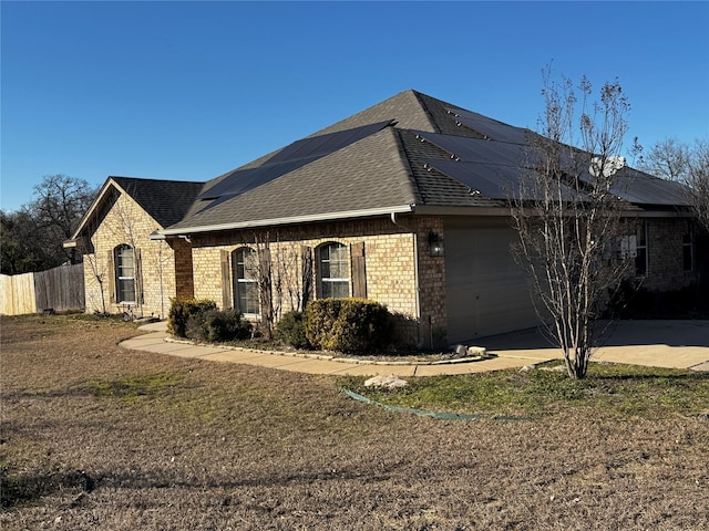 view of side of property featuring a garage, a lawn, and solar panels