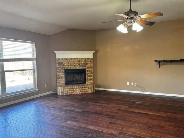 unfurnished living room with dark hardwood / wood-style flooring, a brick fireplace, plenty of natural light, and vaulted ceiling