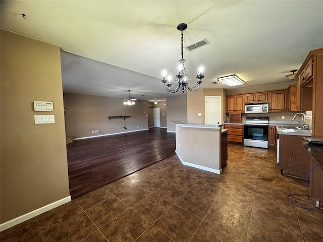 kitchen featuring sink, hanging light fixtures, stainless steel appliances, a center island, and ceiling fan with notable chandelier