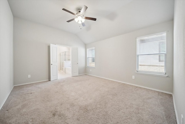 unfurnished bedroom featuring lofted ceiling, ensuite bathroom, light colored carpet, and ceiling fan